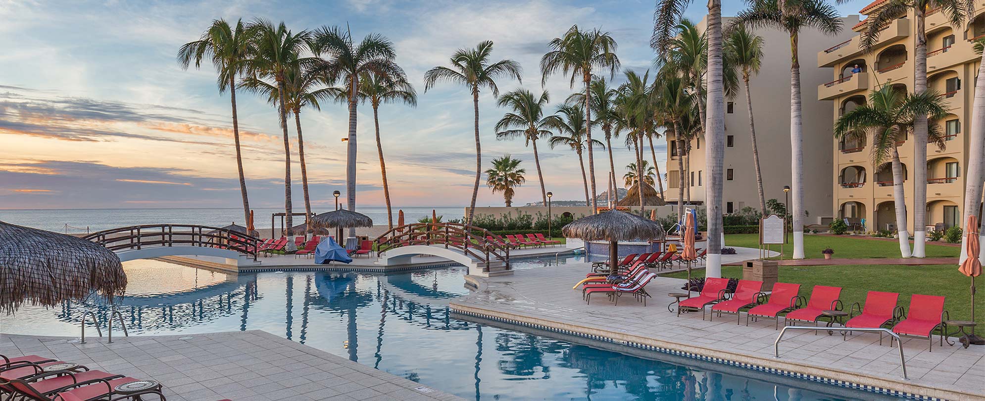 The oceanfront pool surrounded by lounge chairs and palm trees at WorldMark Coral Baja in San José del Cabo, Mexico.
