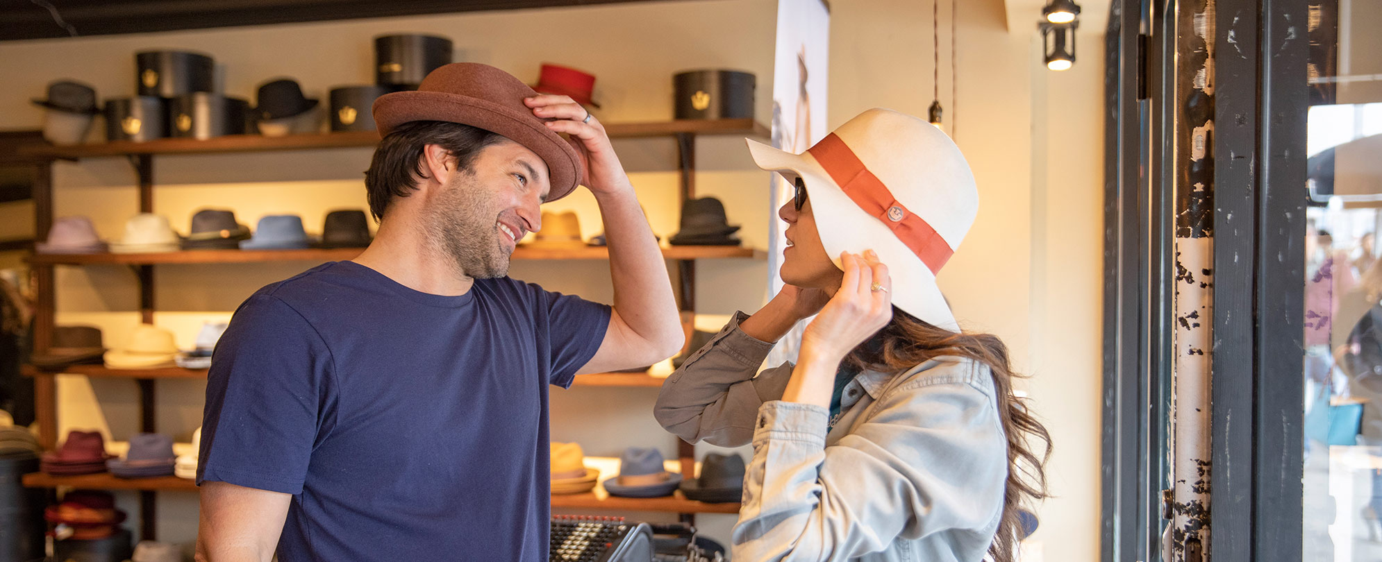 A man and woman try on hats while shopping in Austin, Texas.